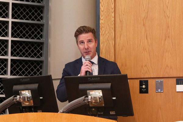 Announcer holding a microphone at a podium at the honors ceremony for the School of Medicine, Medical Education students