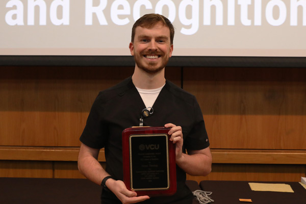 Grant Thesing, medical student, being gifted a plaque for the 2026 Student Leadership Award