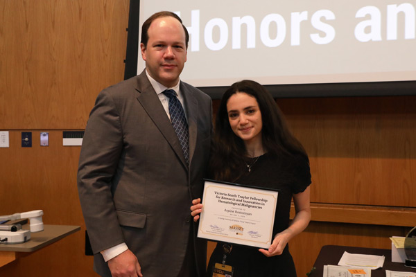M1 student accepting an award for the Victoria Searls Traylor Fellowship while standing next to the award presenter.