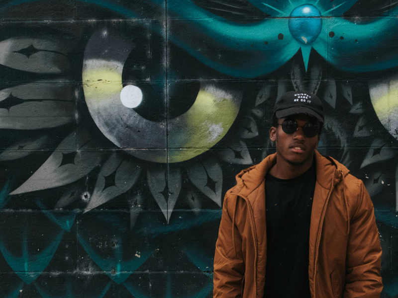 Photo from Pexels of man standing in front of RVA Mural of owl head